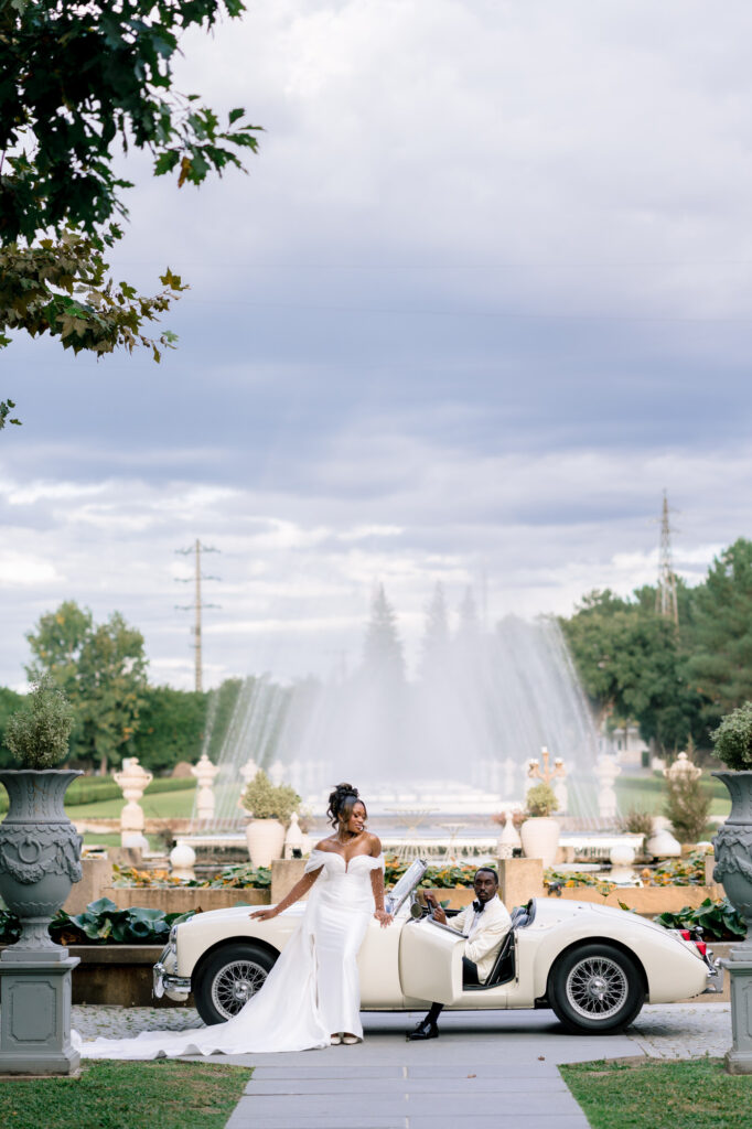 The newlyweds beside the cream MG convertible, in front of Solar da Levada's grand fountain lake