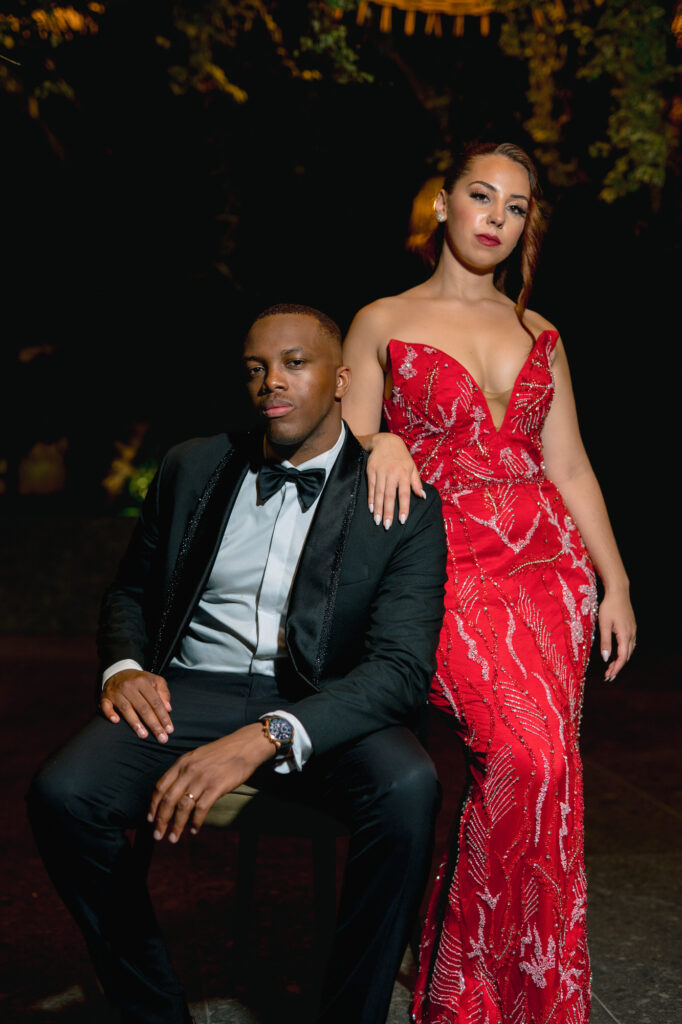 Night portrait of the newlyweds, the bride in a red sequined dress, her hand on the groom's shoulder