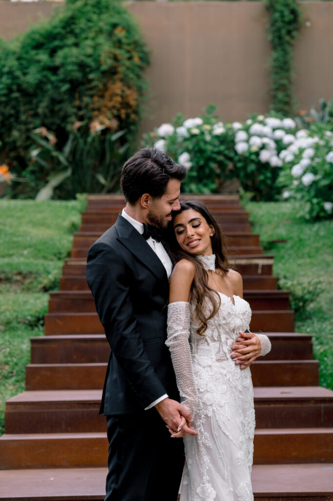 The newlyweds embrace on the staircase, among hydrangeas and greenery