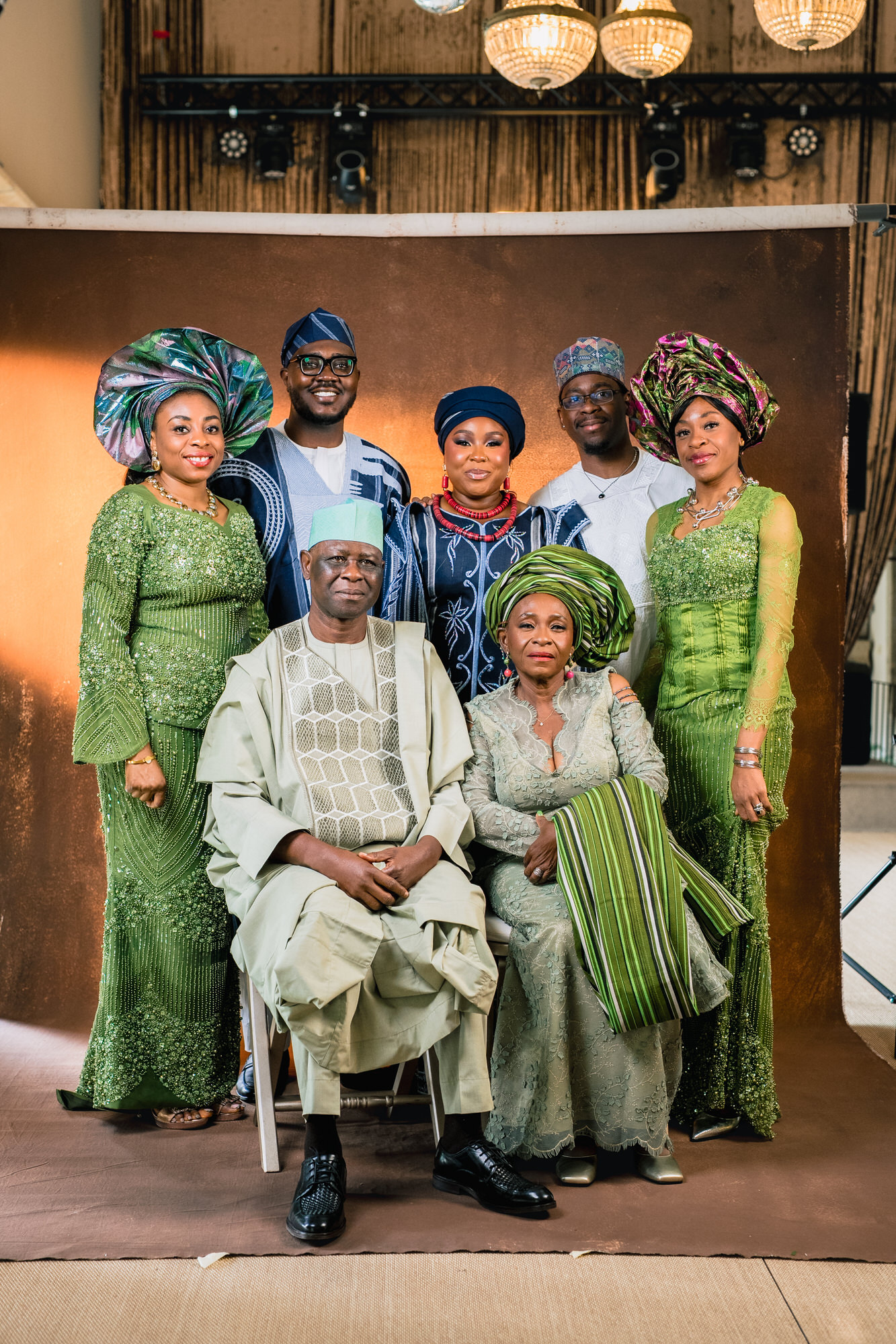 Six Nigerian family members in vibrant green traditional outfits pose for a studio portrait.