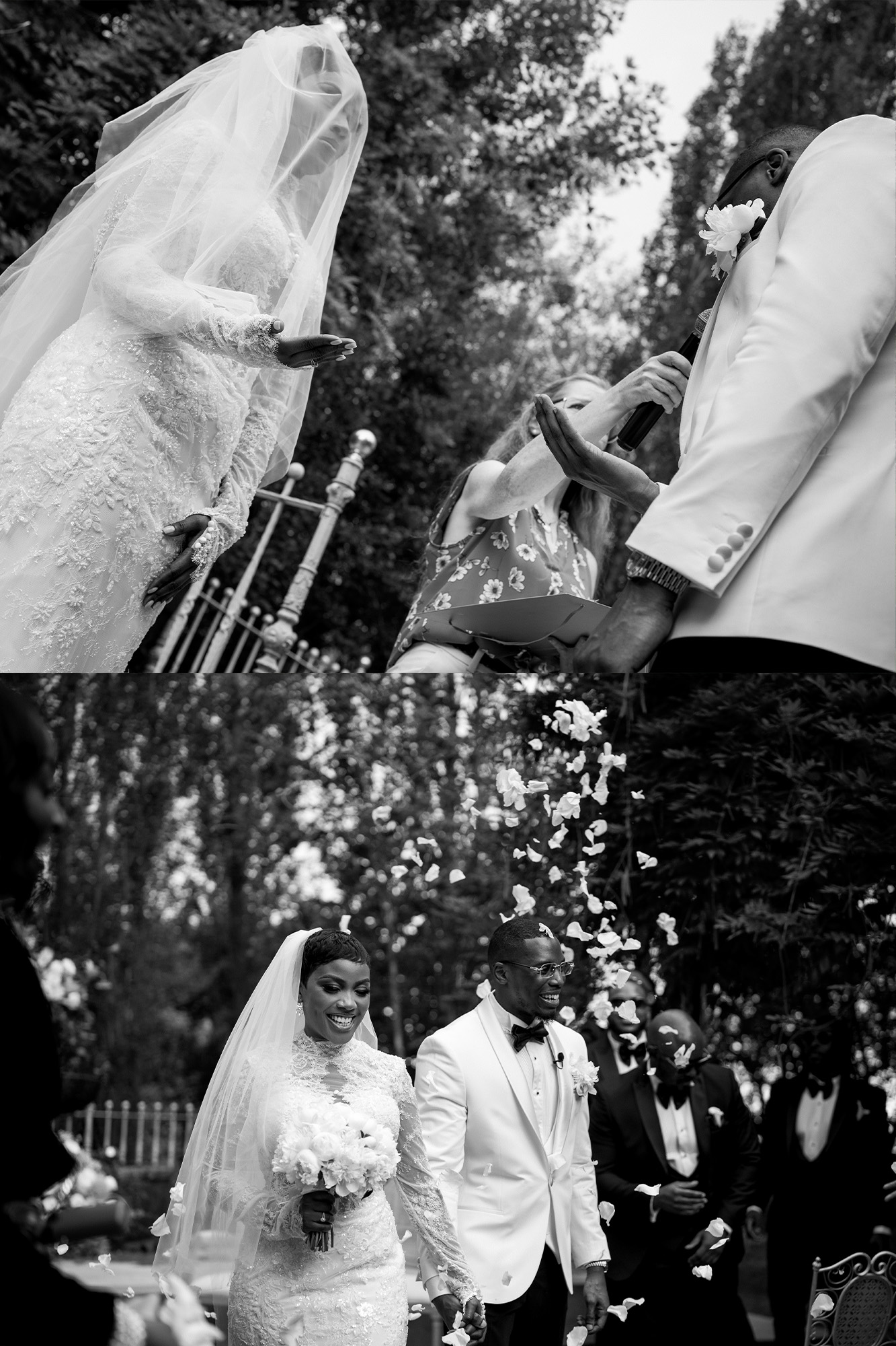 Bride in lace wedding dress and veil walks with groom in a white suit as flower petals are tossed outdoors during a ceremony.