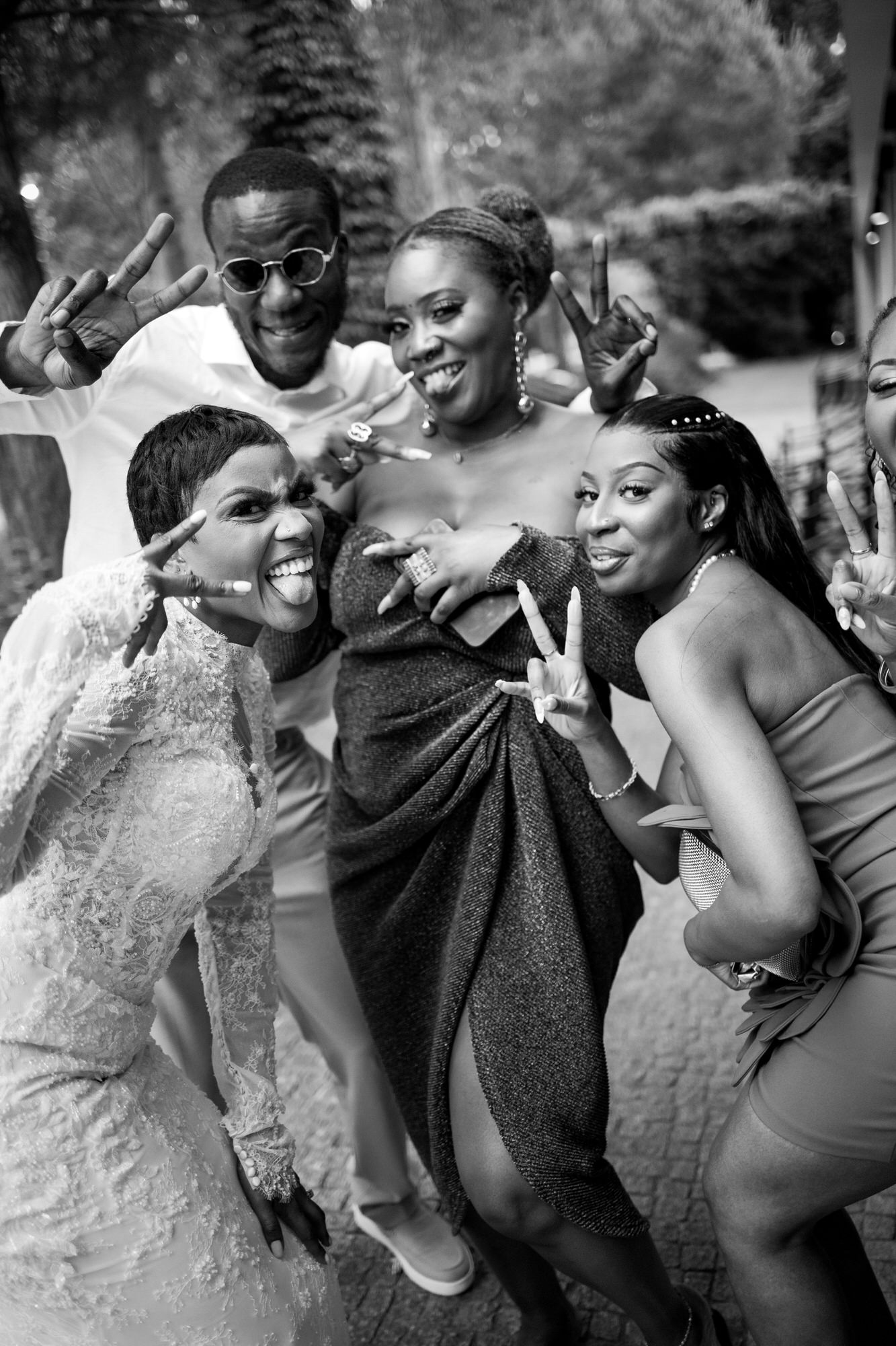 Group of friends at a celebration posing for a photo, flashing peace signs and smiling at the camera.