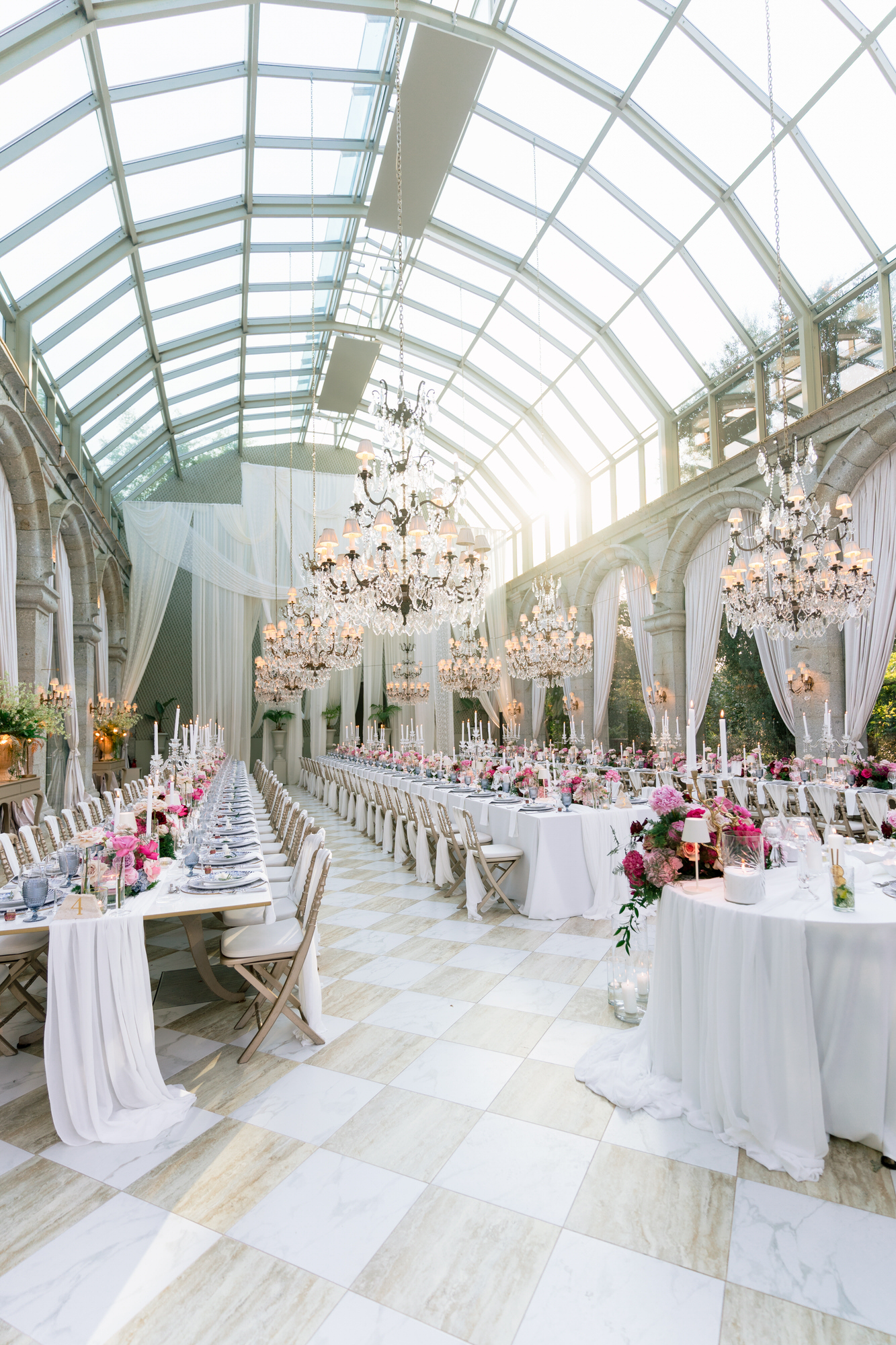 Wide view of the glass-roofed reception hall at Solar da Levada, with long tables, flowers and chandeliers
