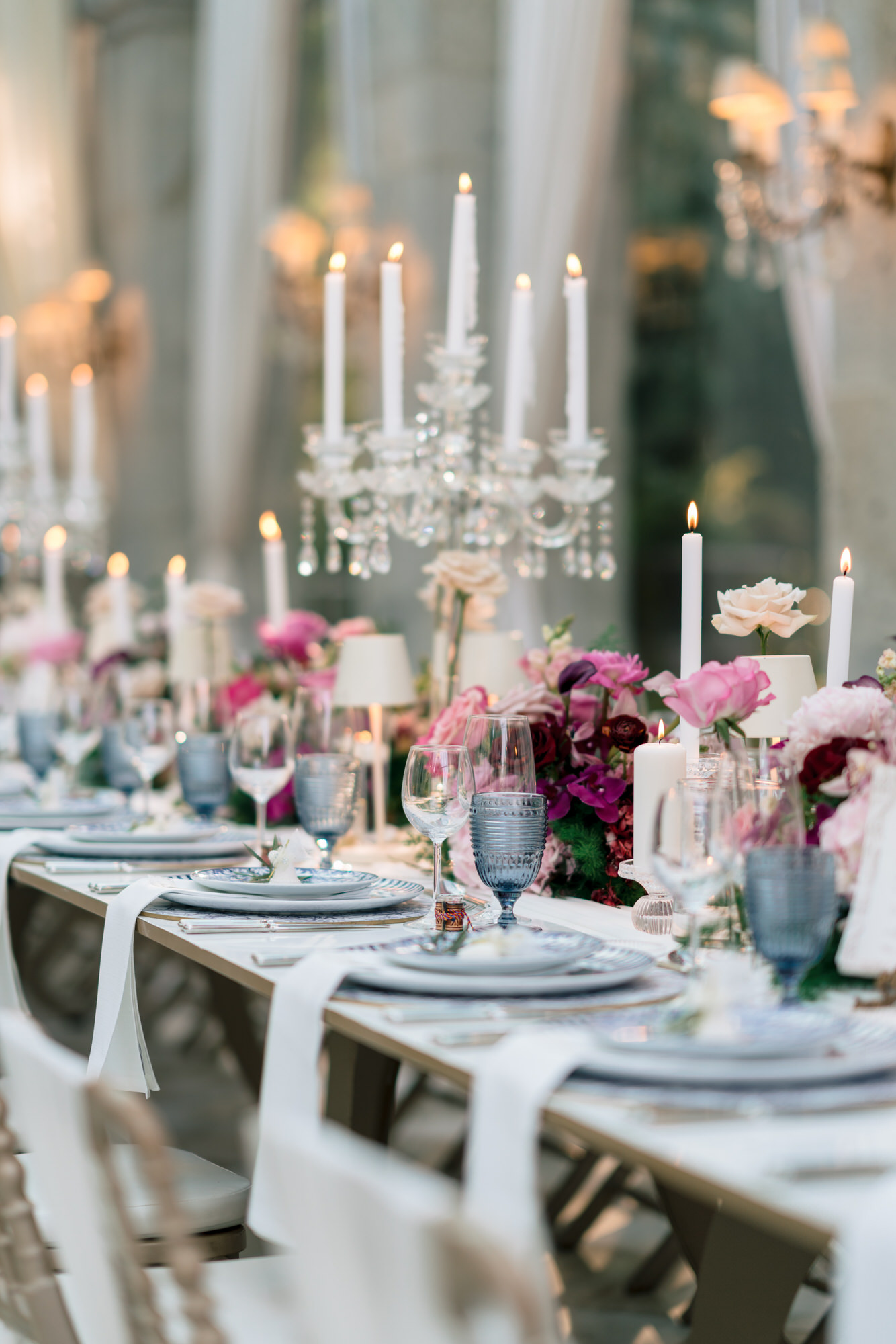 A long reception table with candelabras, pink flowers and blue-patterned plates