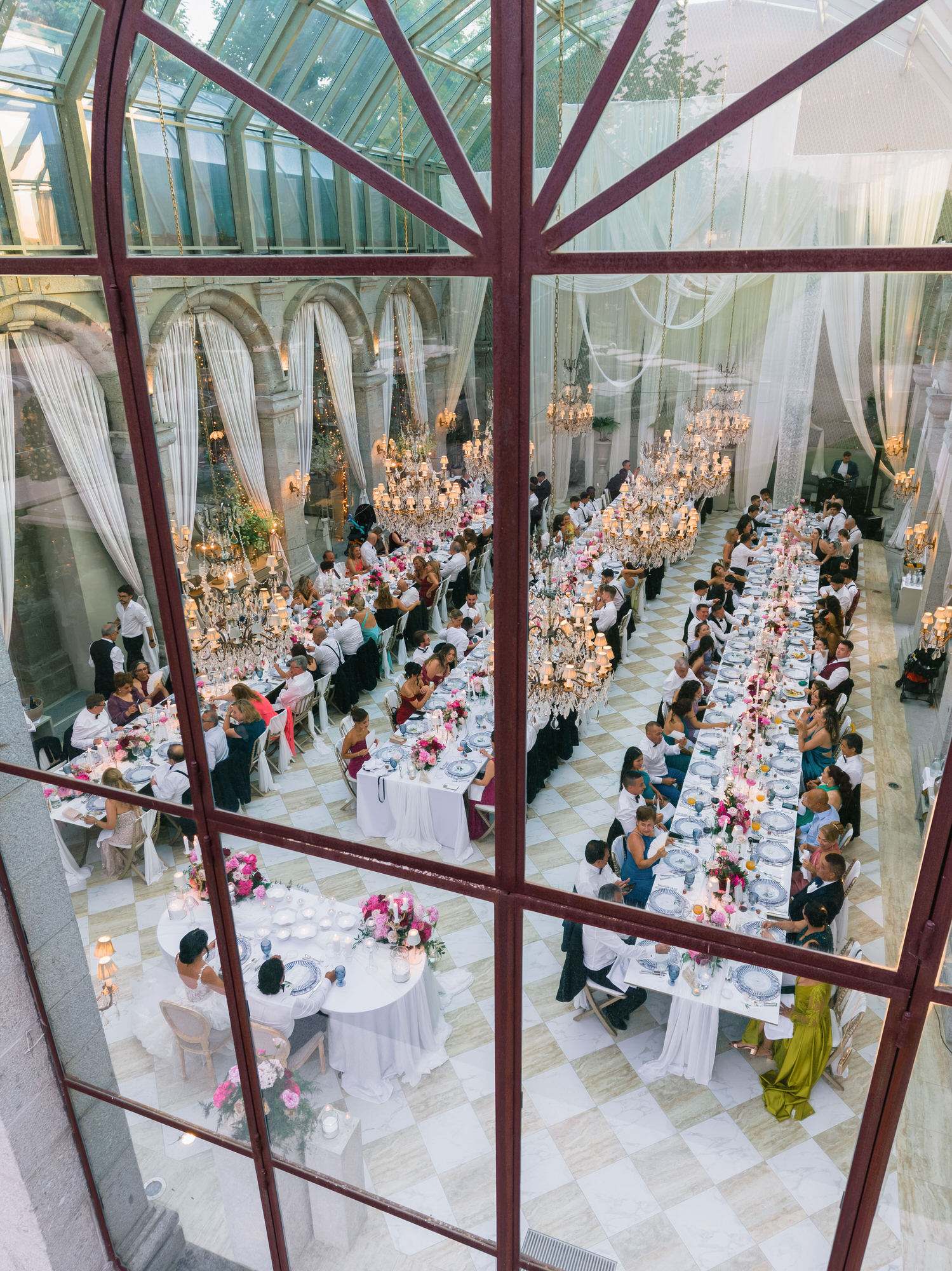 Overhead view through the glass roof of the long reception tables set with flowers and candles