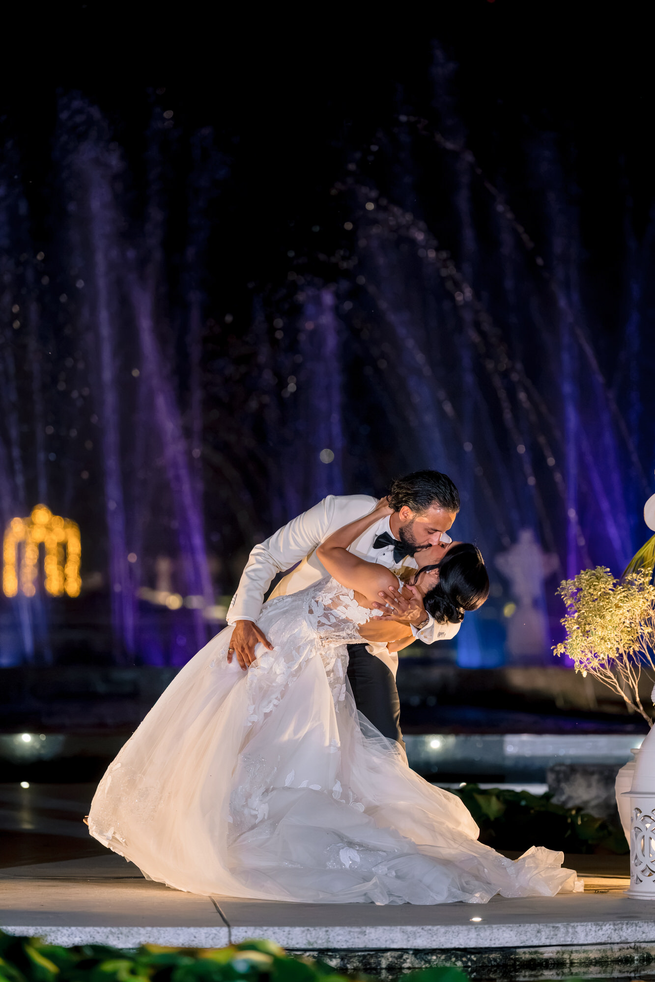 The couple dancing close at night, the bride’s gown swirling in blue light