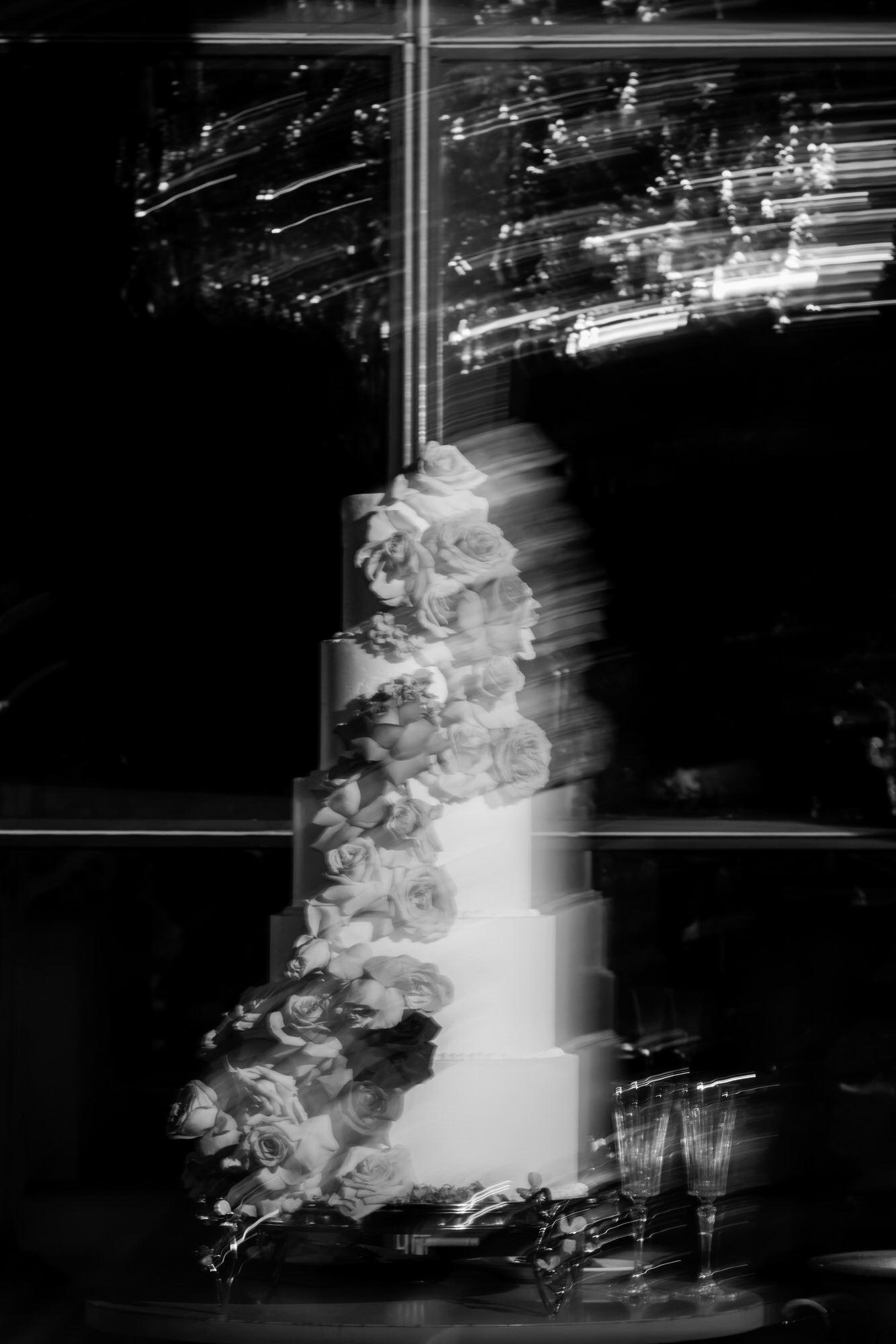 Long-exposure black-and-white image of the tiered wedding cake with light trails in the dark