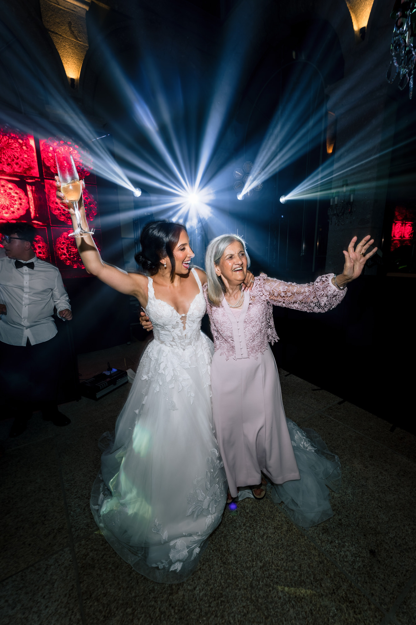 The bride dancing with an older guest under blue stage lights