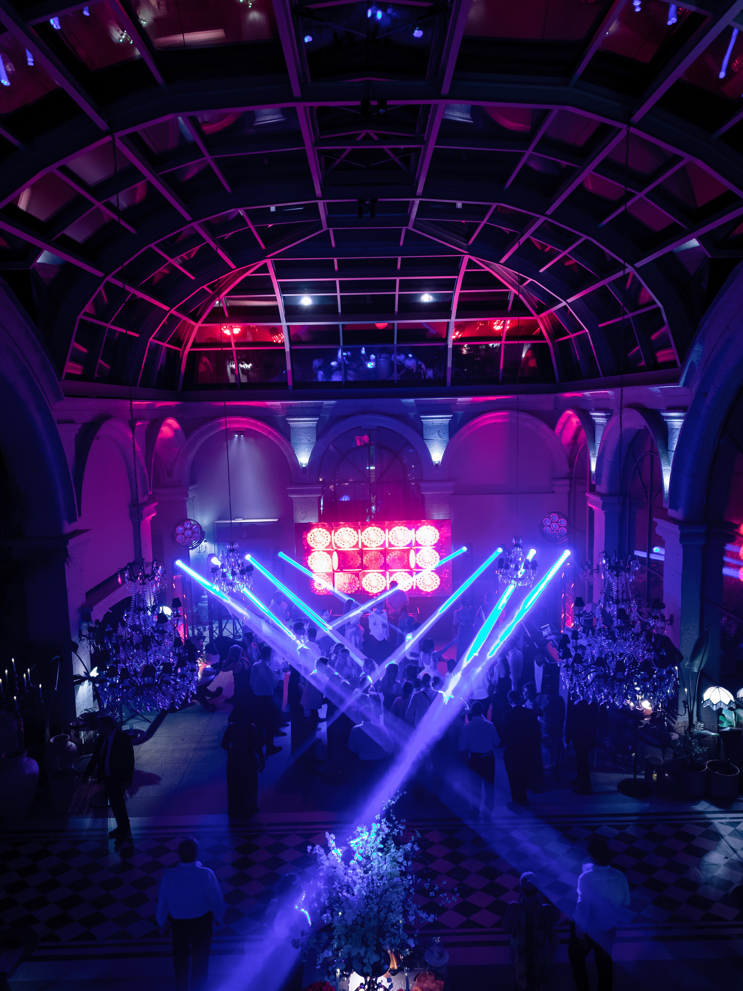 The dance floor lit in blue and magenta, with laser beams and a lit stage