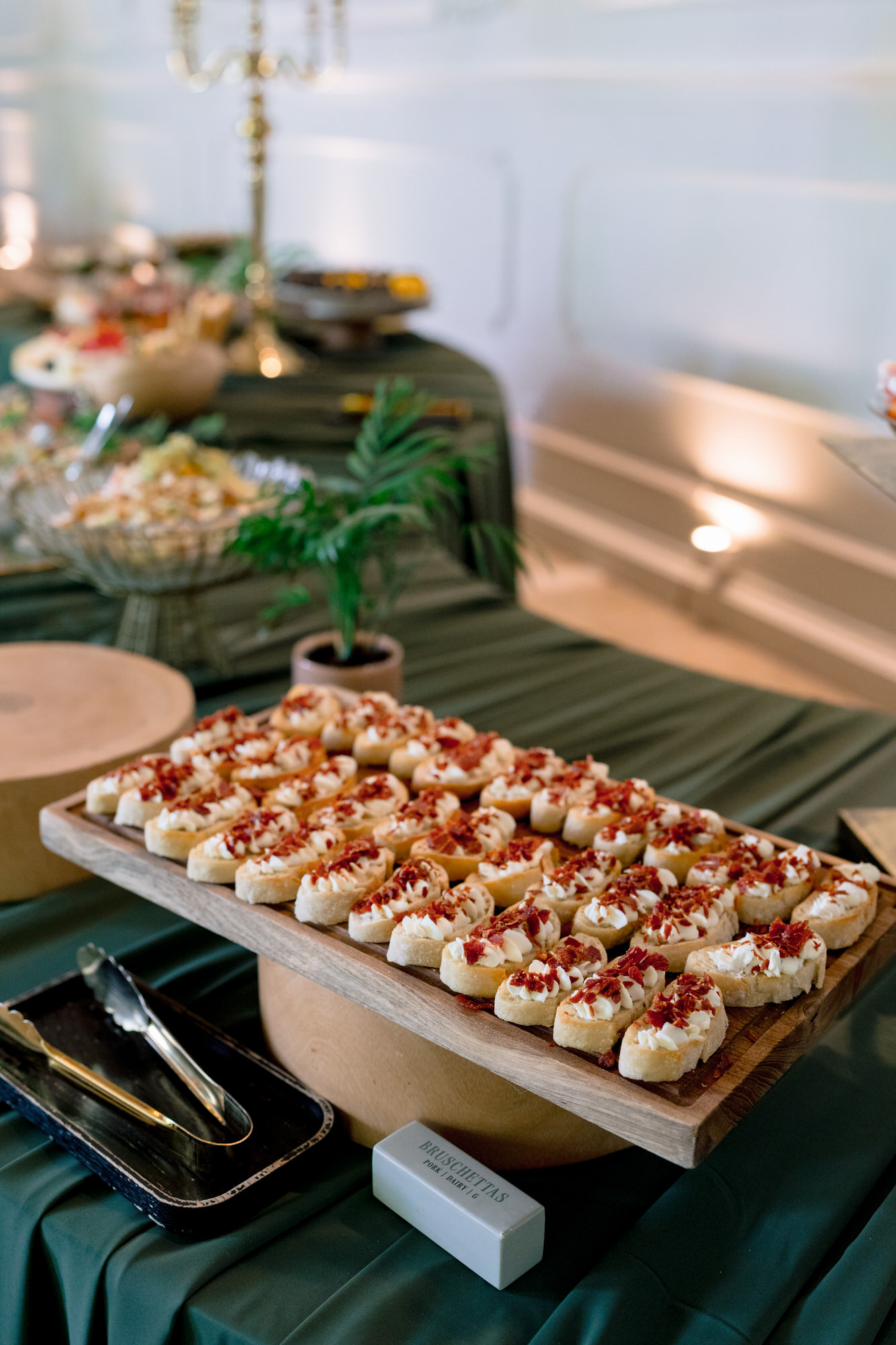 A wooden board of small savoury pastries on a table dressed in emerald green linen