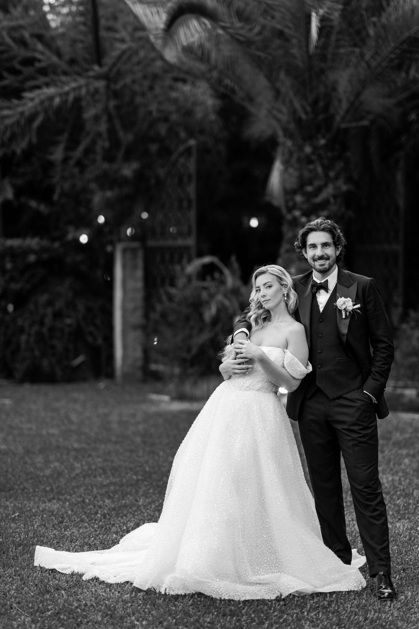 Black-and-white portrait of the couple in the garden, the bride in a full ball gown