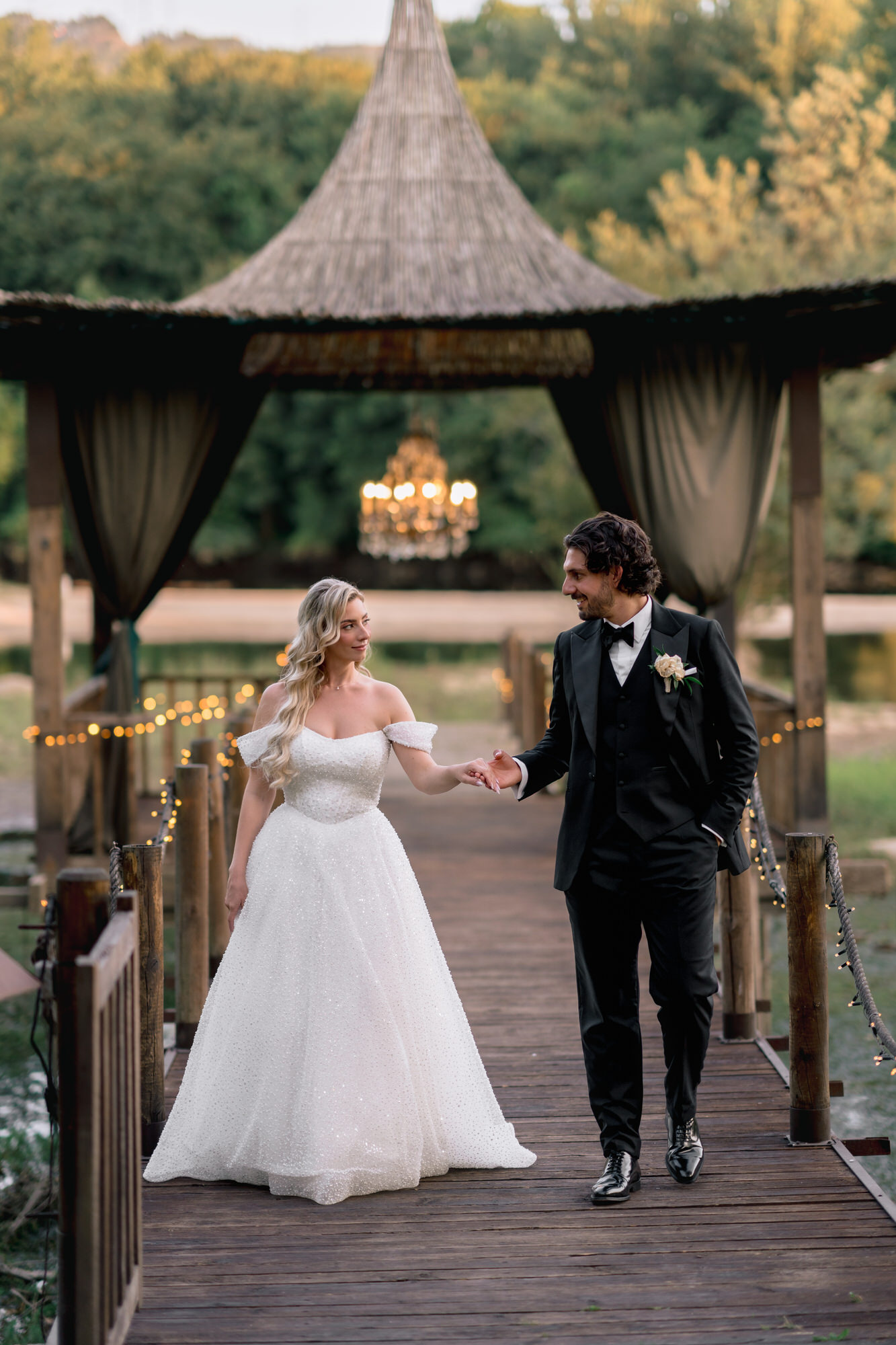 The couple walking along a wooden bridge towards a gazebo in the garden