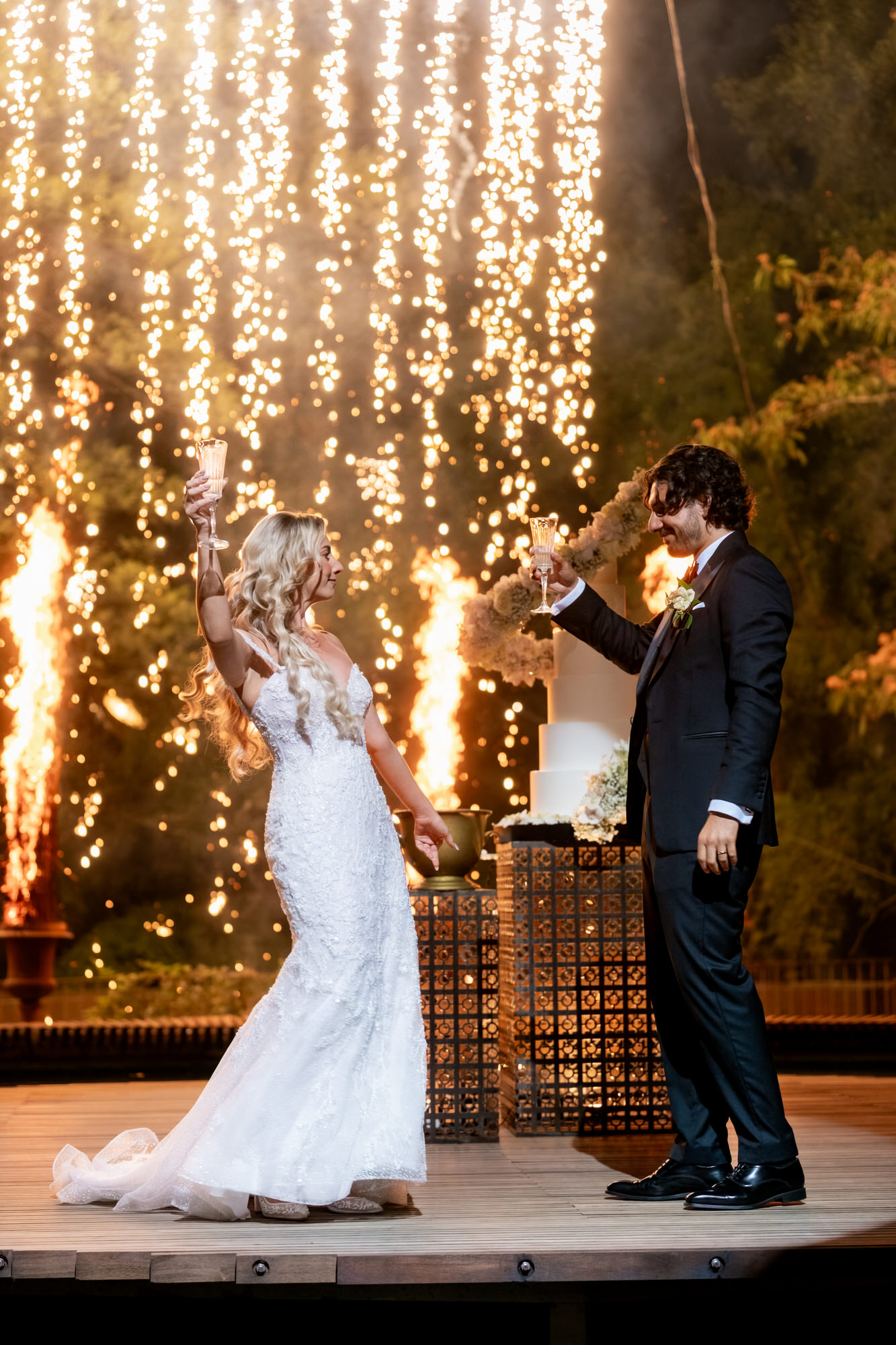 The newlyweds on the circular platform with fountains of sparks rising behind them