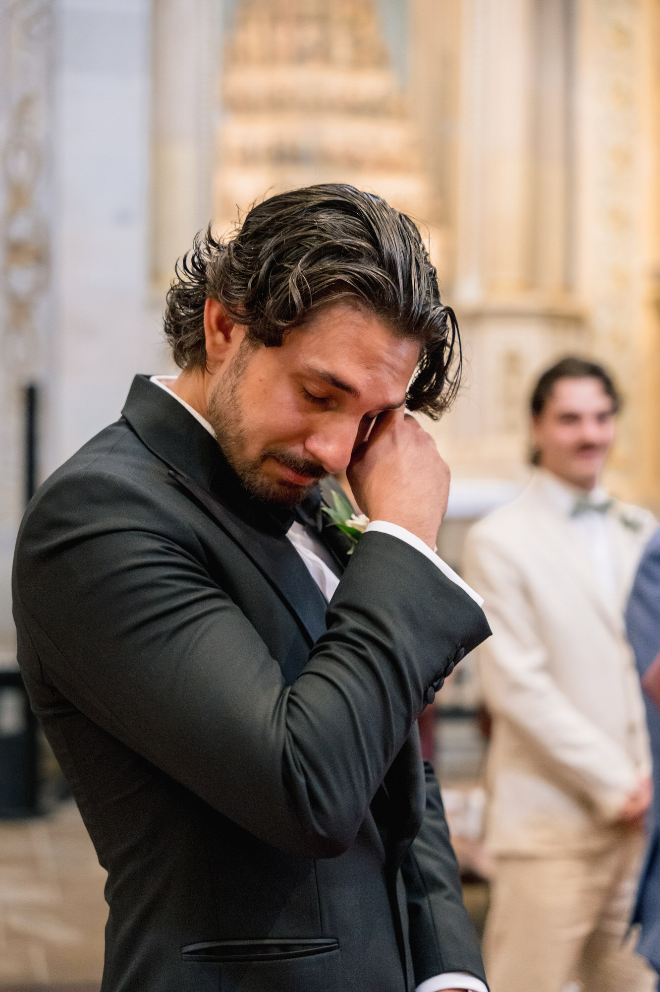 The groom wiping away a tear as he sees the bride at the church