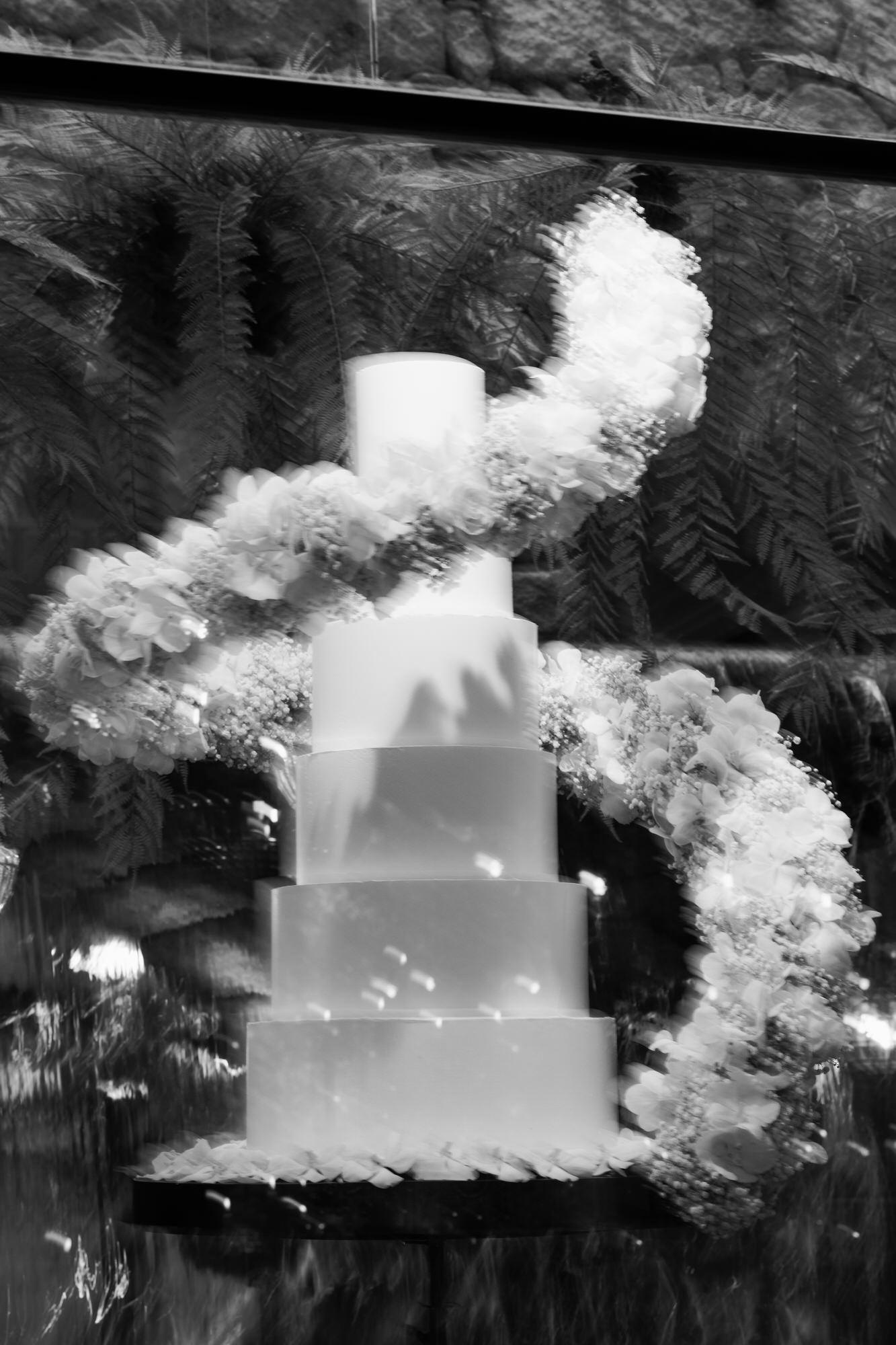 Black-and-white image of the tiered wedding cake wrapped in a spiral floral garland