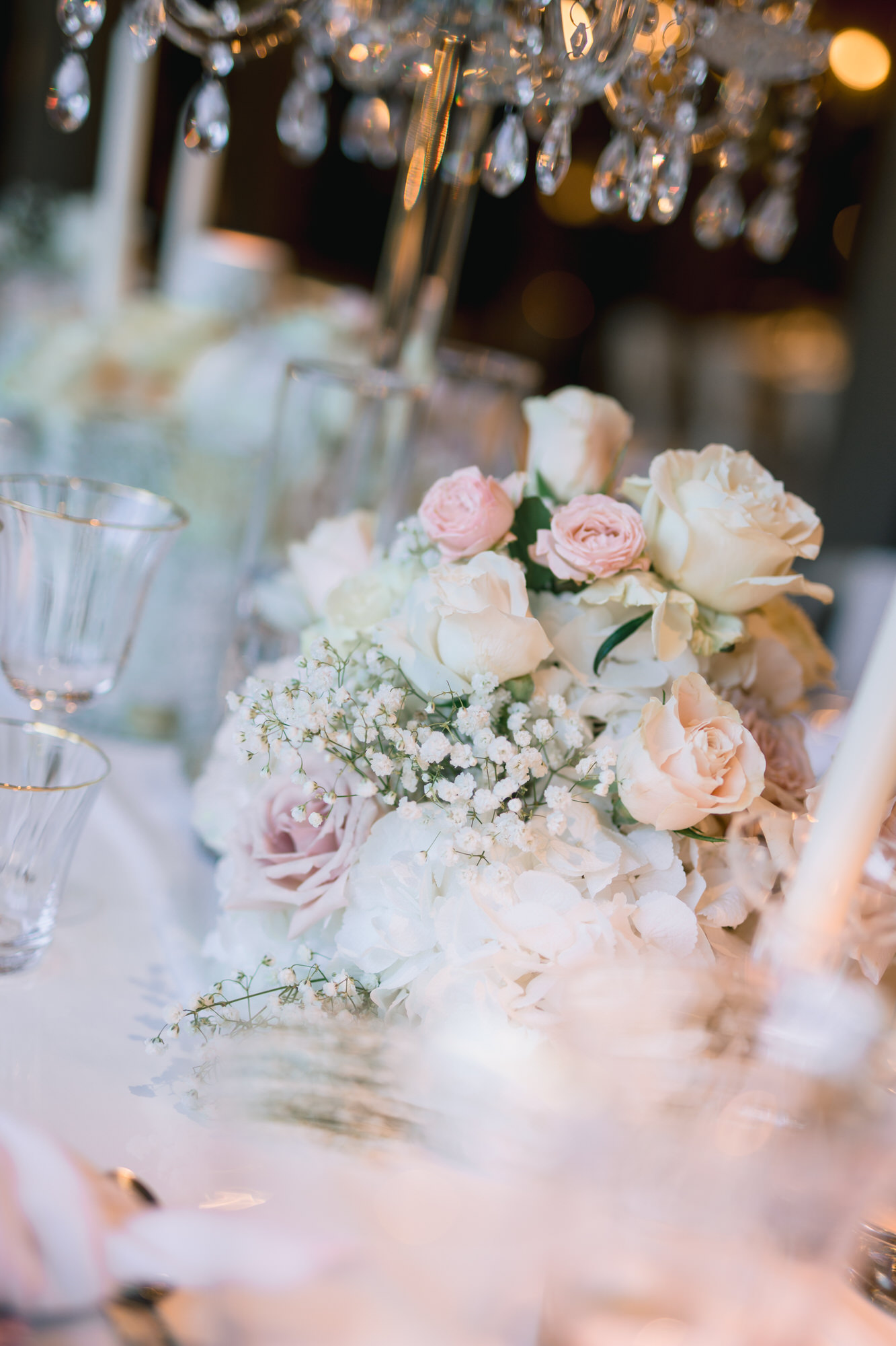 Close-up of pale pink roses and crystal glassware on a reception table