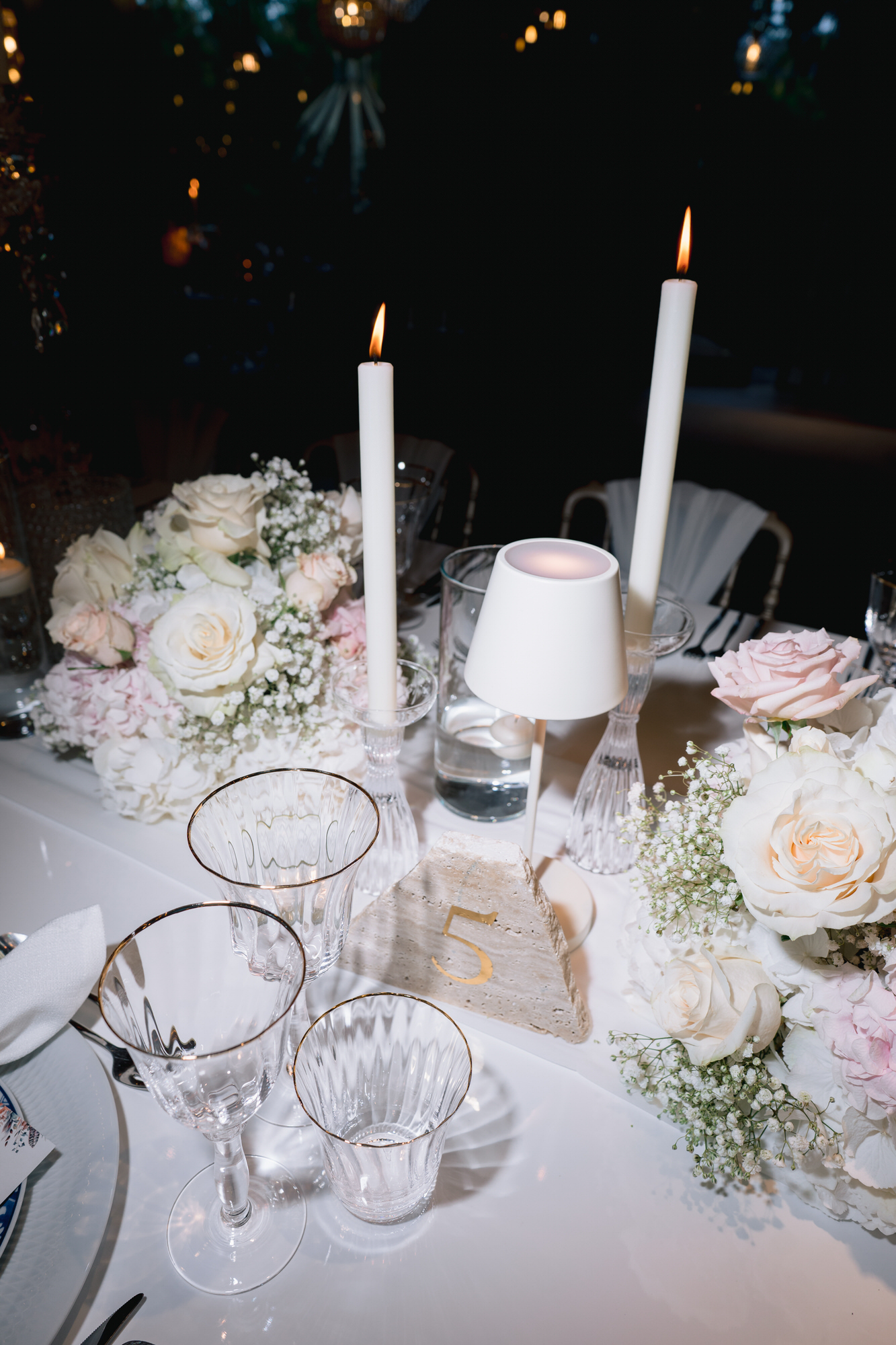 Candles, white roses and glassware arranged on the dinner table