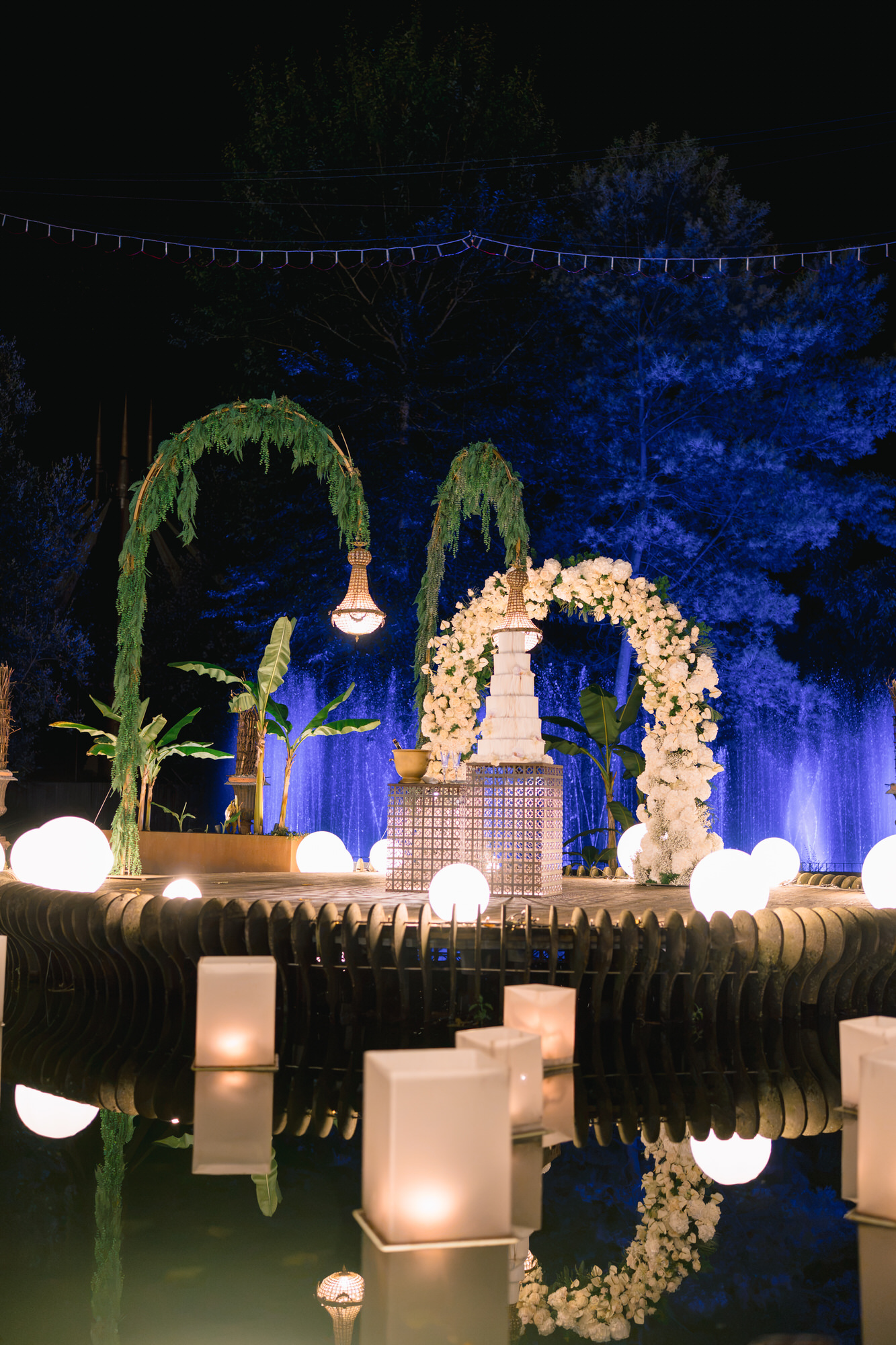 Night view of the lake with floral arches and floating candles reflected on the water