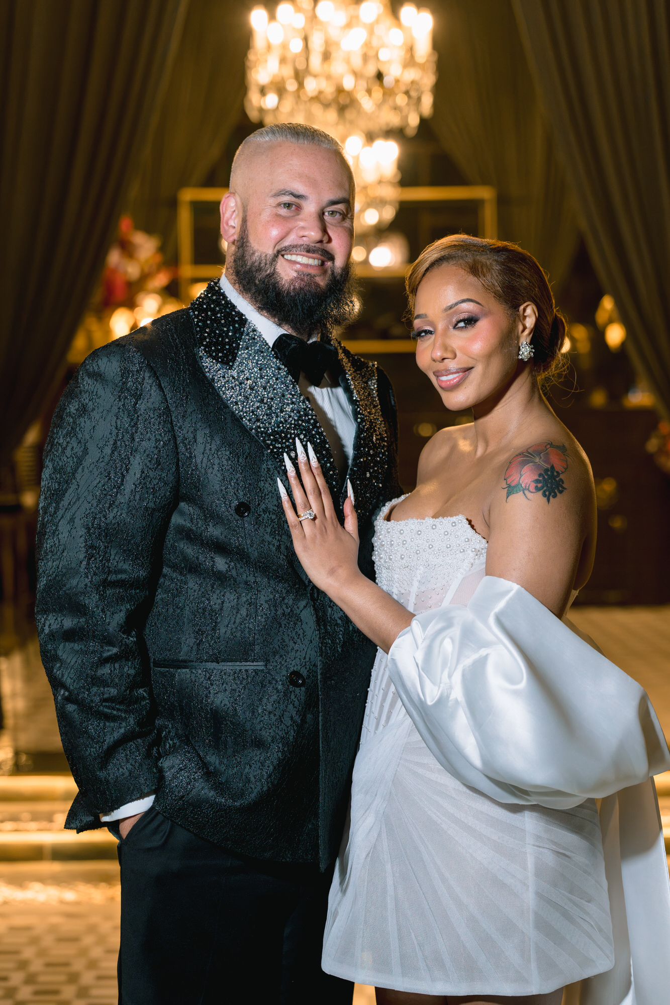 Portrait of the couple, Thomas in a dark green jacquard tuxedo and Mahlet in a short white dress with puff sleeves
