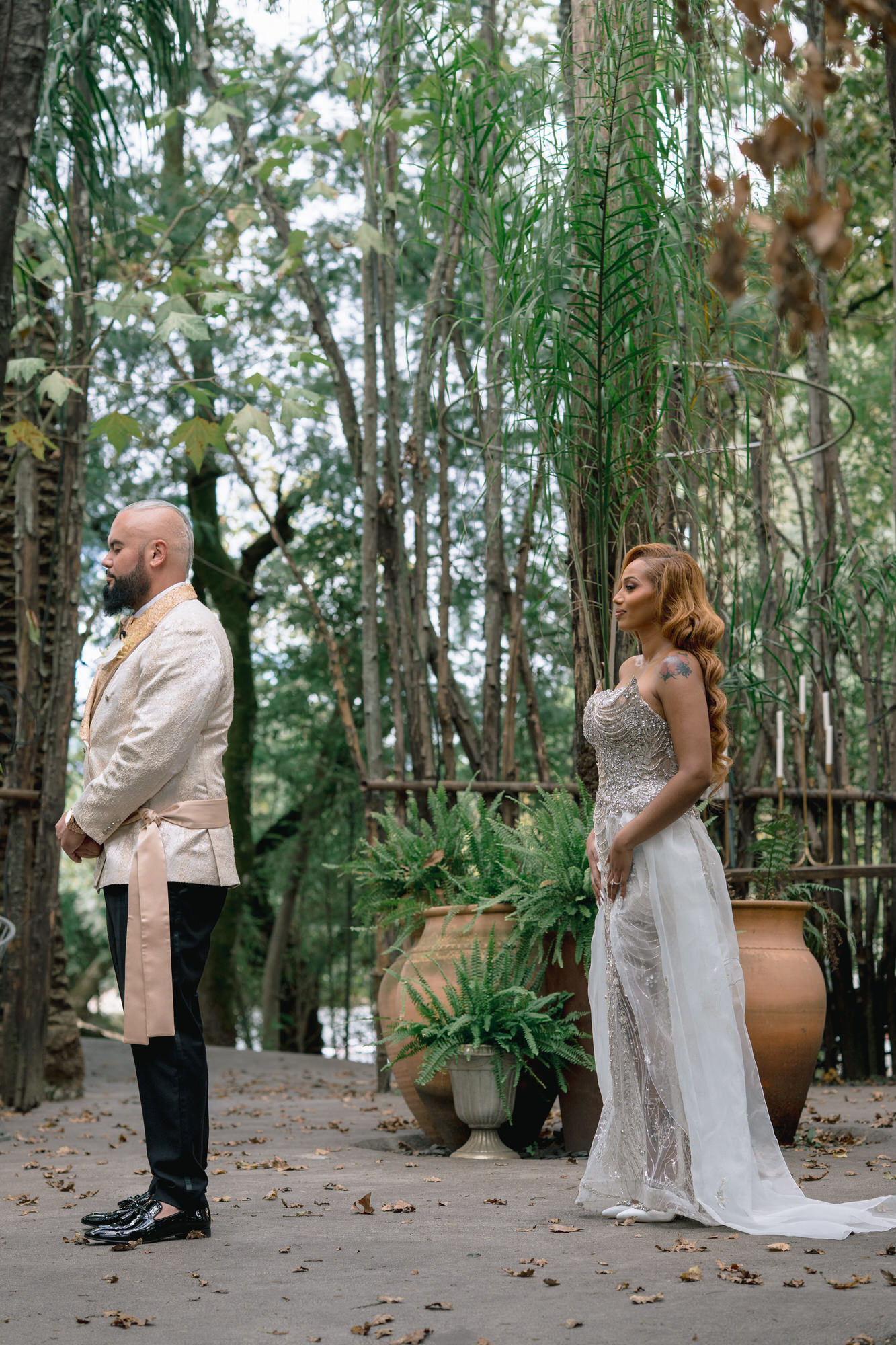 Mahlet and Thomas standing together among the trees, he in a cream jacket and she in a sparkling gown